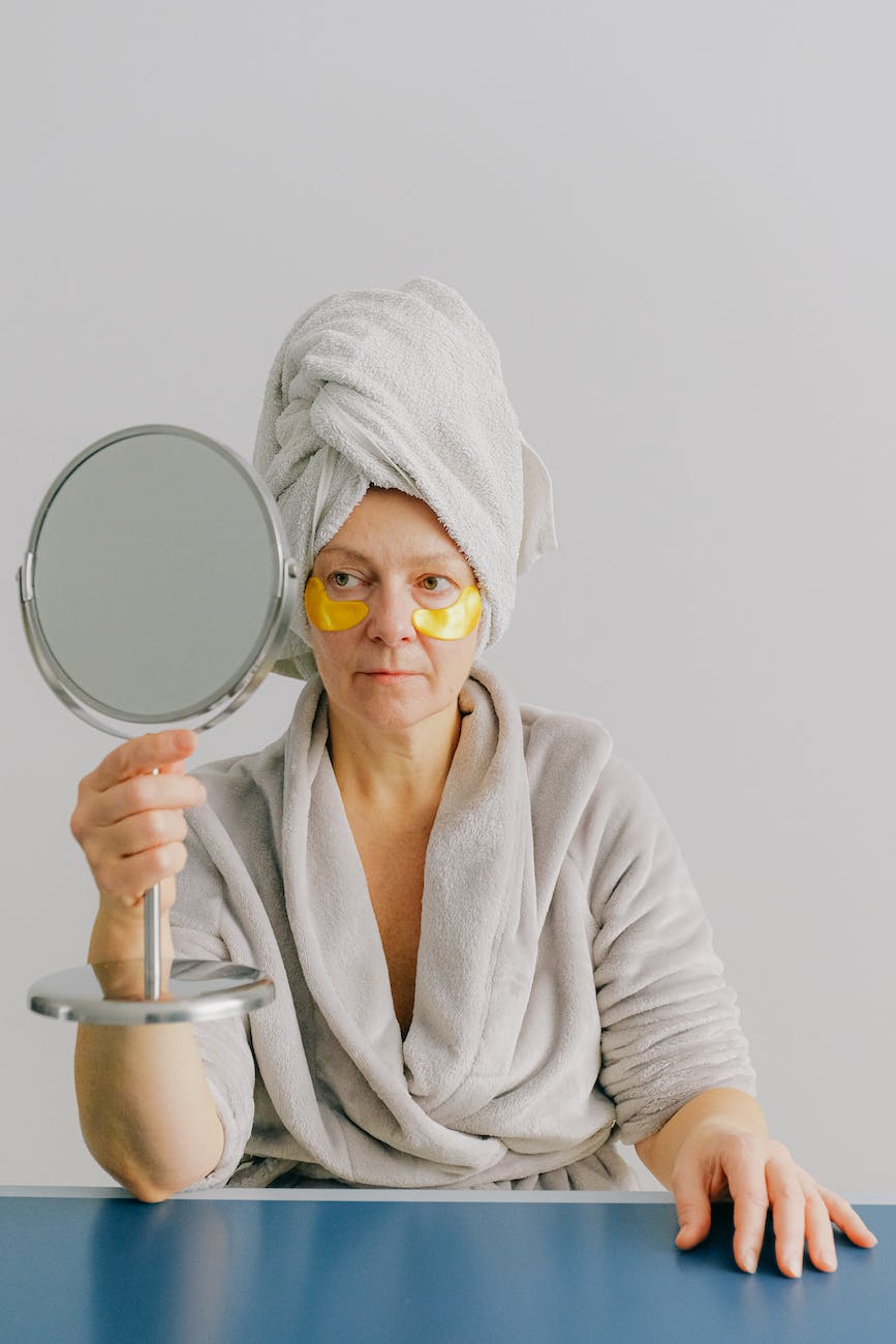 aged woman with eye patches looking in mirror
